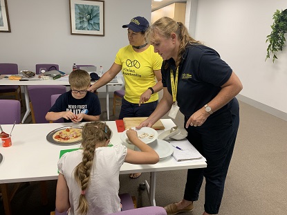 VA staff instruct children how to make pizza and use kitchen equipment