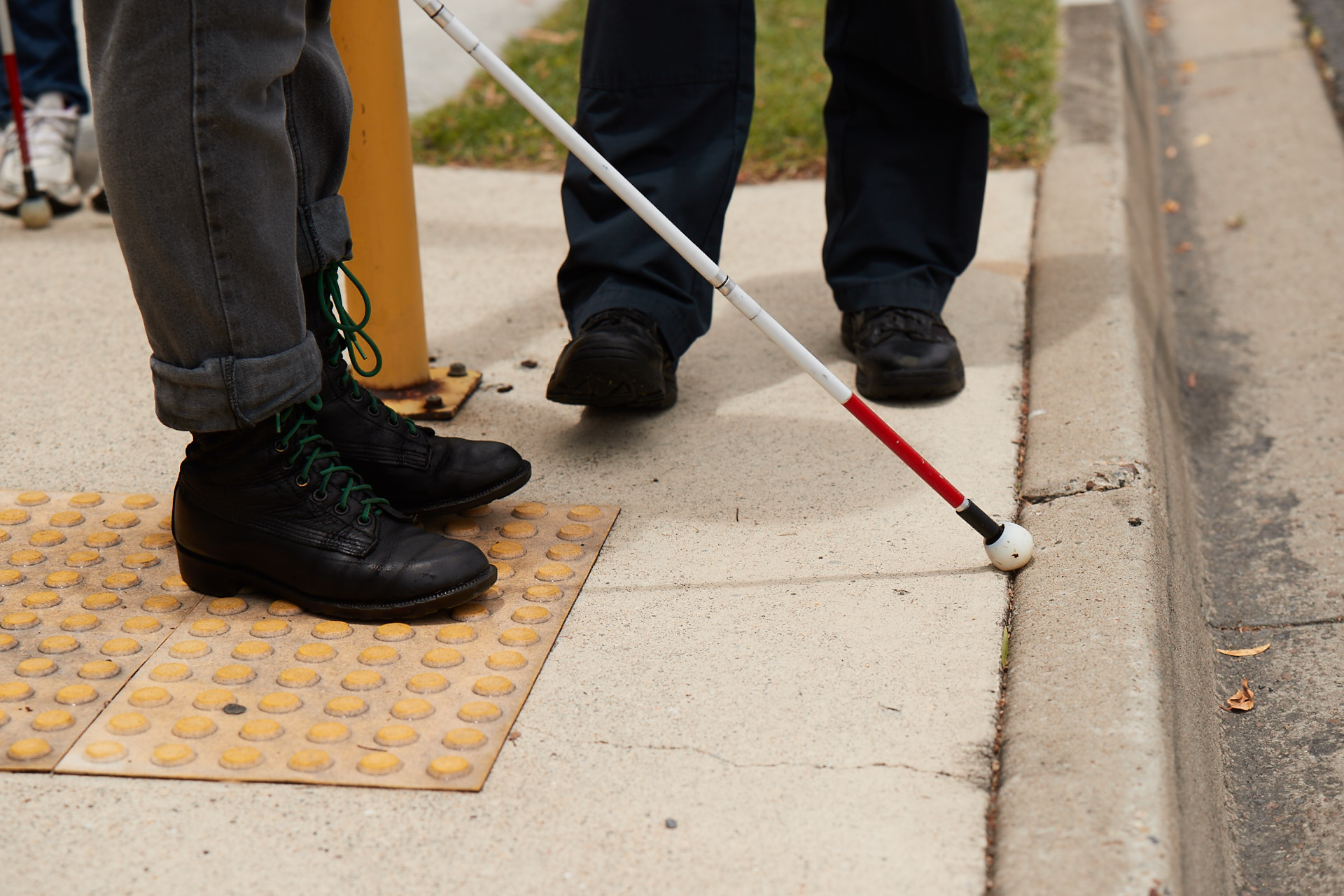 The end of white cane at the edge of a gutter