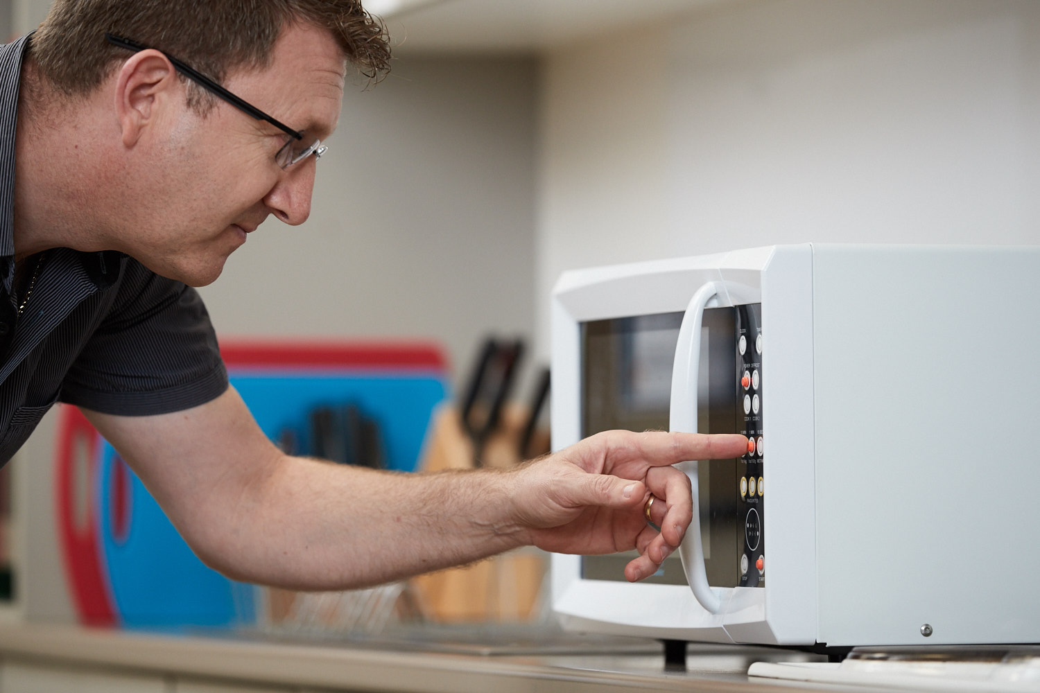 "A man uses a microwave fitted with tactile dots"