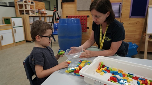 A young male VA client uses LEGO Braille with a VA staff member