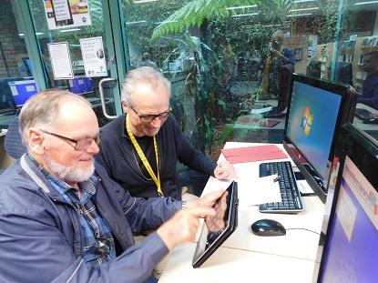 A VA staff memner shows an older amn how to use an ipad