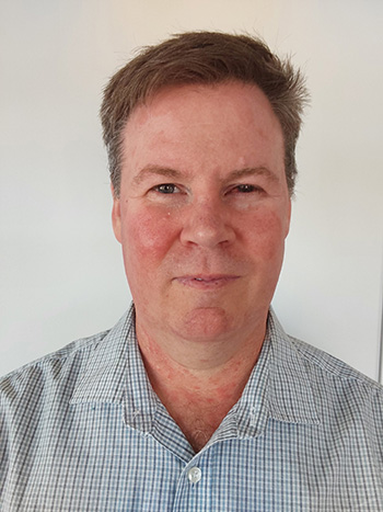 A middle-aged man with short brown hair looks at the camera