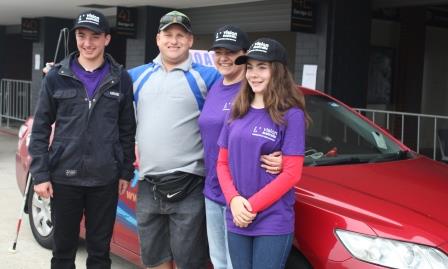 Volunteers Ethan, Adelina and Eliza Holloway stand in front of a red car with Chris Richards