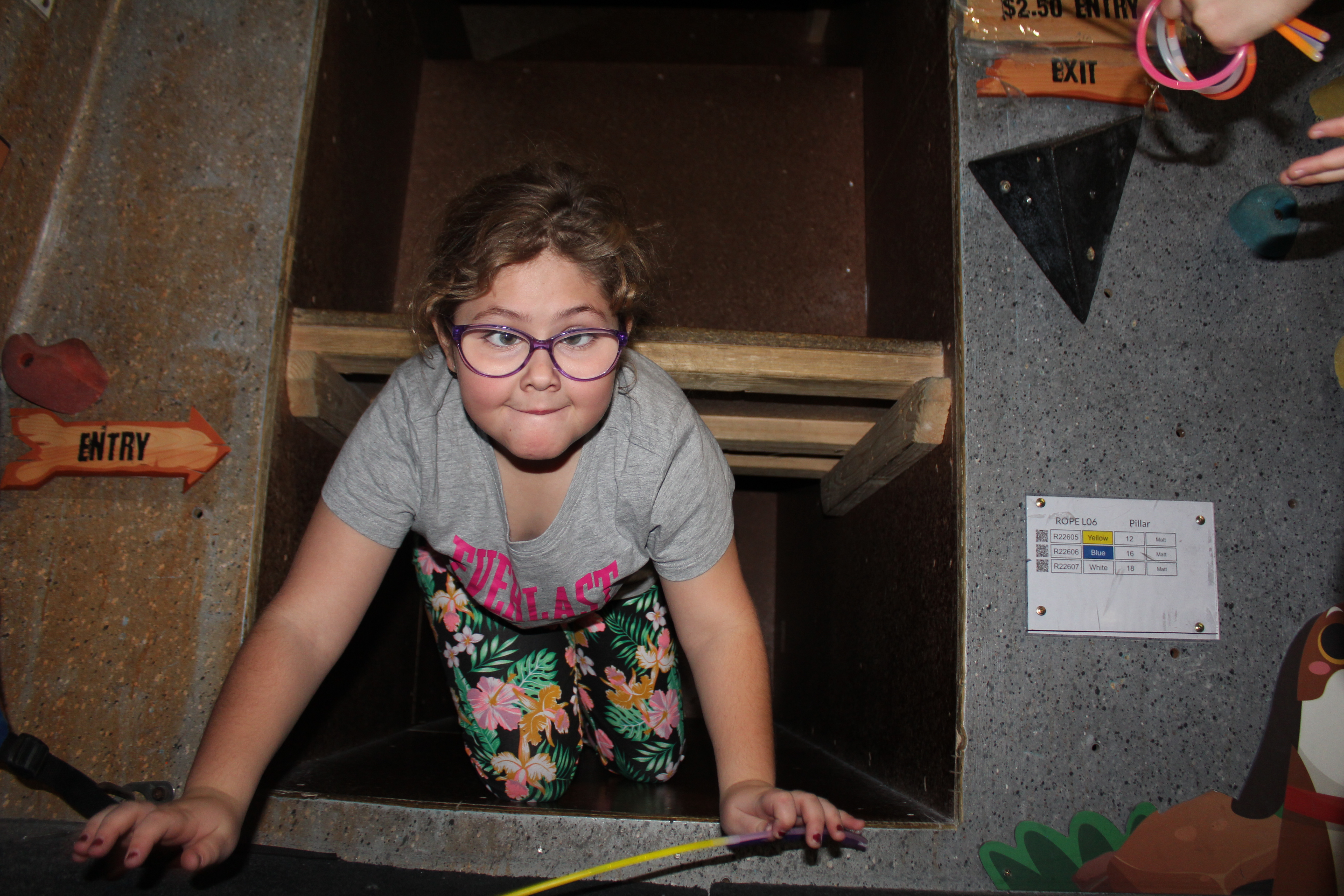 Child climbing through a space marked 'entry', looking up at the camera