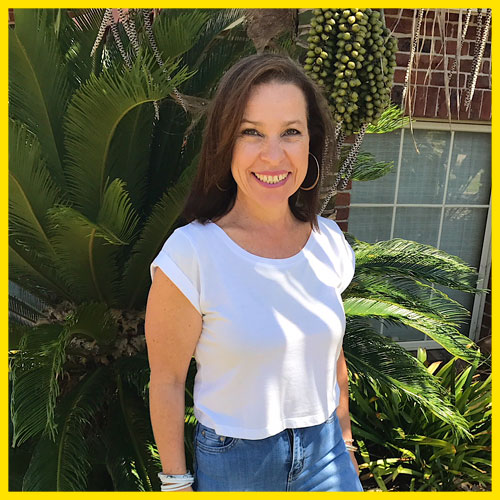 Profile photo of Marisa smiling outside standing in front of a plant