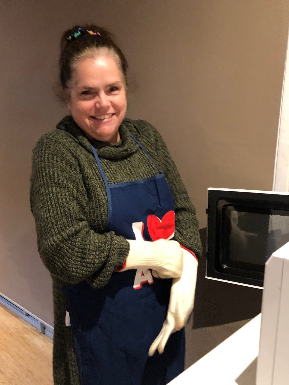 Linda pulling on gloves in the kitchen ready to cook