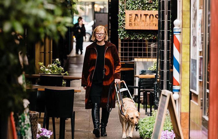 A lady navigating a crowded street with a Seeing Eye Dog.