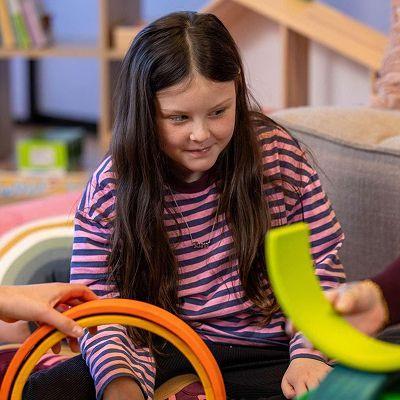 A little girl sitting on the ground, playing with toys