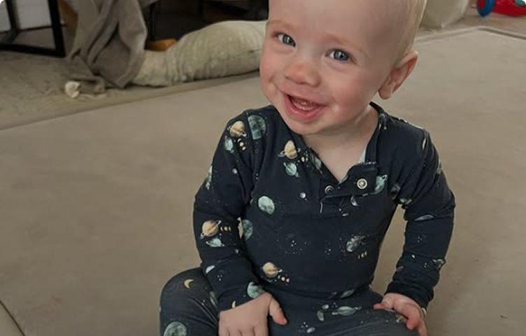 Flynn is sitting on the floor smiling