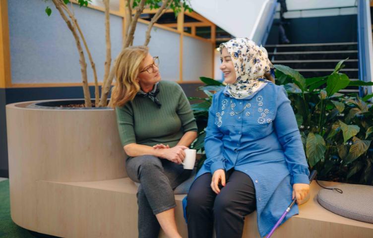 A woman sits with her female service provider, having a conversation while smiling.
